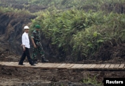 FILE - Indonesian President Joko Widodo (L) inspects a canal in Pulang Pisau, Central Kalimantan, Oct. 31, 2015. Widodo’s administration is seen by many indigenous people as dragging its feet on the return of forest land to indigenous people.