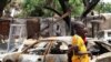 FILE - Two boys stand in front of burnt cars in Michika, a city recaptured from Boko Haram by the Nigeria military. 