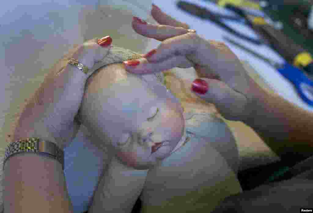 Kerry Stuart restores a plastic doll by rubbing a compound into its cracked head at Sydney&#39;s Doll Hospital, Australia.