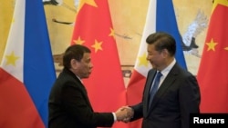 FILE - Philippine President Rodrigo Duterte (L) and Chinese President Xi Jinping shake hands after a signing ceremony held in Beijing, Oct. 20, 2016. 
