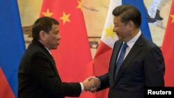 FILE - Philippine President Rodrigo Duterte (L) and Chinese President Xi Jinping shake hands after a signing ceremony held in Beijing, Oct. 20, 2016. 