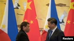 FILE - Philippine President Rodrigo Duterte (L) and Chinese President Xi Jinping shake hands after a signing ceremony held in Beijing, Oct. 20, 2016.