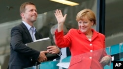 FILE - German Chancellor Angela Merkel waves after watching the group G World Cup soccer match between Germany and Portugal at the Arena Fonte Nova in Salvador, Brazil, June 16, 2014.