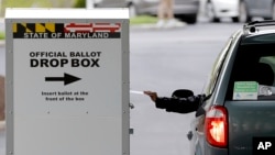 A motorist drops off a mail-in ballot outside of a voting center during the 7th Congressional District special election, Tuesday, April 28, 2020, in Windsor Mill, Md. (AP Photo/Julio Cortez)