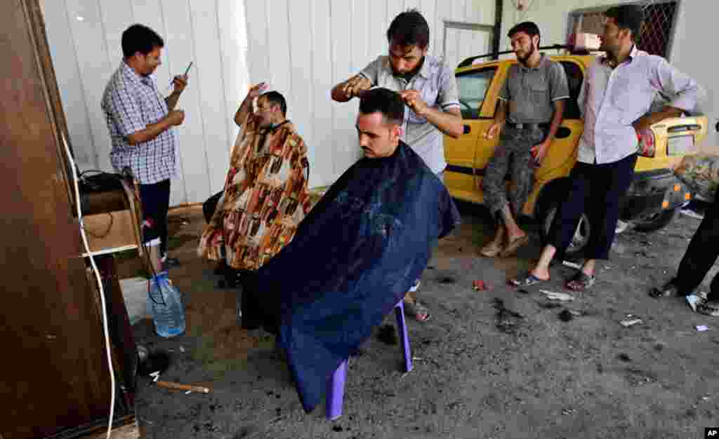 Syrian barbers who fled their homes shave the heads of other displaced men at the Bab Al-Salameh border crossing, in hopes of entering one of the refugee camps in Turkey.
