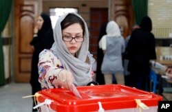 An Iranian woman casts her ballot for the parliamentary runoff elections in a polling station at the city of Qods about 12 miles (20 kilometers) west of Tehran, April 29, 2016.