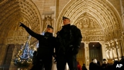 French Police officers stand near the entrance of Notre Dame Cathedral as worshippers arrive for the Christmas eve mass in Paris, Dec. 24, 2016. Security was tightened at Christmas across Europe after a deadly truck attack on a market in Berlin.