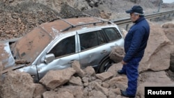 A rescue worker inspects a car caught under a landslide after an earthquake and tsunami hit the northern port of Iquique, Chile, April 2, 2014. 