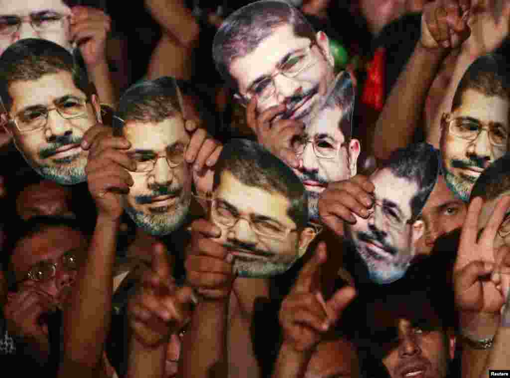 Members of the Muslim Brotherhood and supporters of deposed Egyptian President Mohamed Morsi hold up masks of him as they gather at the Rabaa Adawiya square, where they are camping, in Cairo, July 13, 2013.