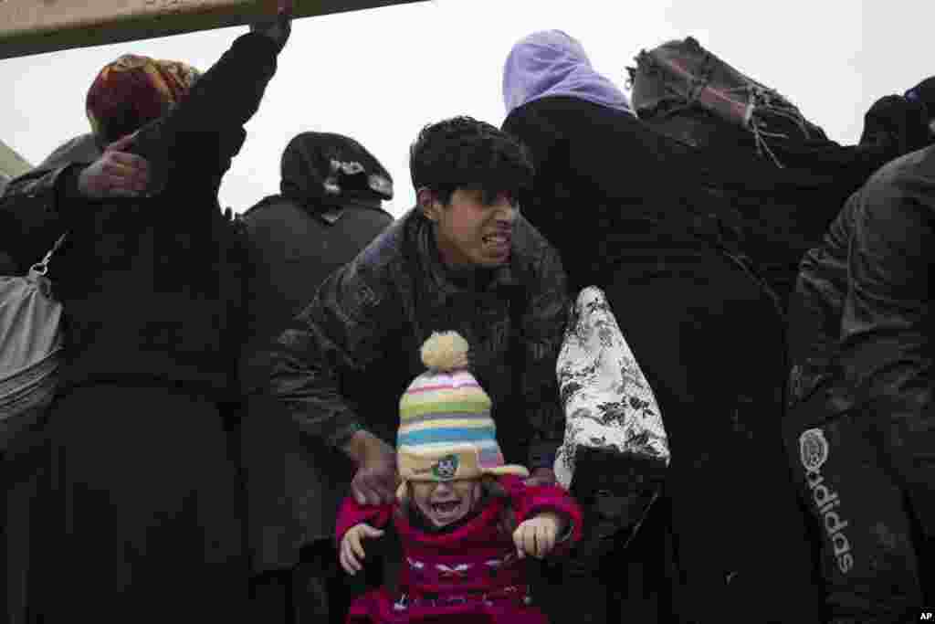 Displaced Iraqis, fleeing fighting between Iraqi security forces and Islamic State militants, board a truck before being taken to a camp on the western side of Mosul.