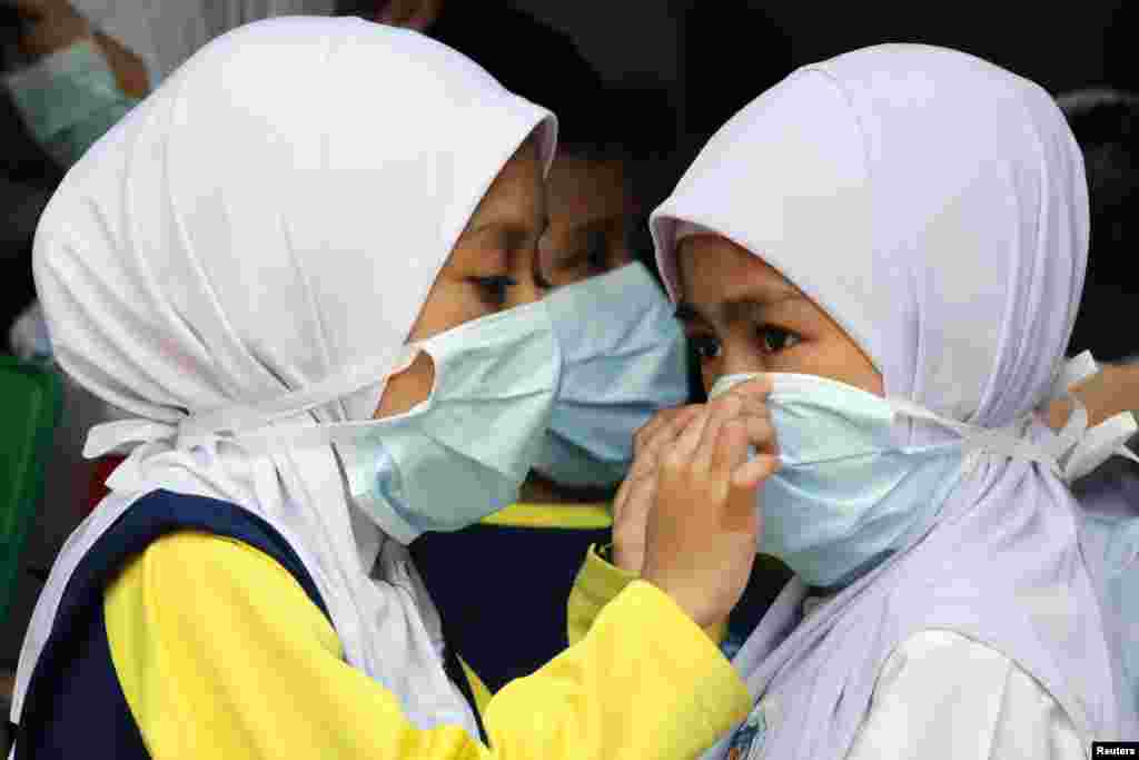Schoolchildren cover their faces with masks as haze shrouds Kuala Lumpur, Malaysia.