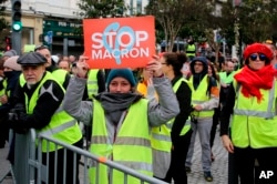A demonstrator wearing her yellow vest holds a placard during a visit by French Foreign Minister Jean-Yves Le Drian in Biarritz, southwestern France, Dec. 18, 2018.