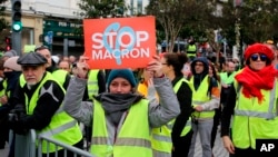 A demonstrator wearing her yellow vest holds a placard during a visit by French Foreign Minister Jean-Yves Le Drian in Biarritz, southwestern France, Dec. 18, 2018. 