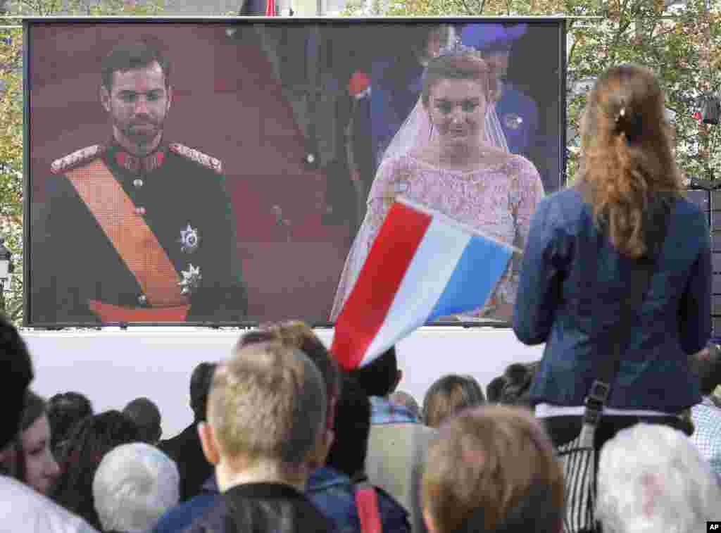 A girl waves a Luxembourg flag as she watches the royal wedding on a video screen at square in Luxembourg, October 20, 2012. 