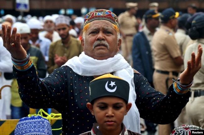 FILE - A man offers Eid al-Fitr prayers marking the end of the holy fasting month of Ramadan outside a railway station, in Mumbai, India, June 16, 2018.