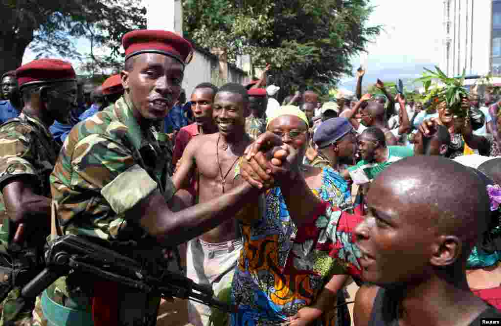 People greet soldiers as they celebrate in Bujumbura, May 13, 2015. Crowds poured onto the streets of Burundi&#39;s capital to celebrate after a general said he was dismissing President Pierre Nkurunziza for violating the constitution by seeking a third term in office, a Reuters witness said.