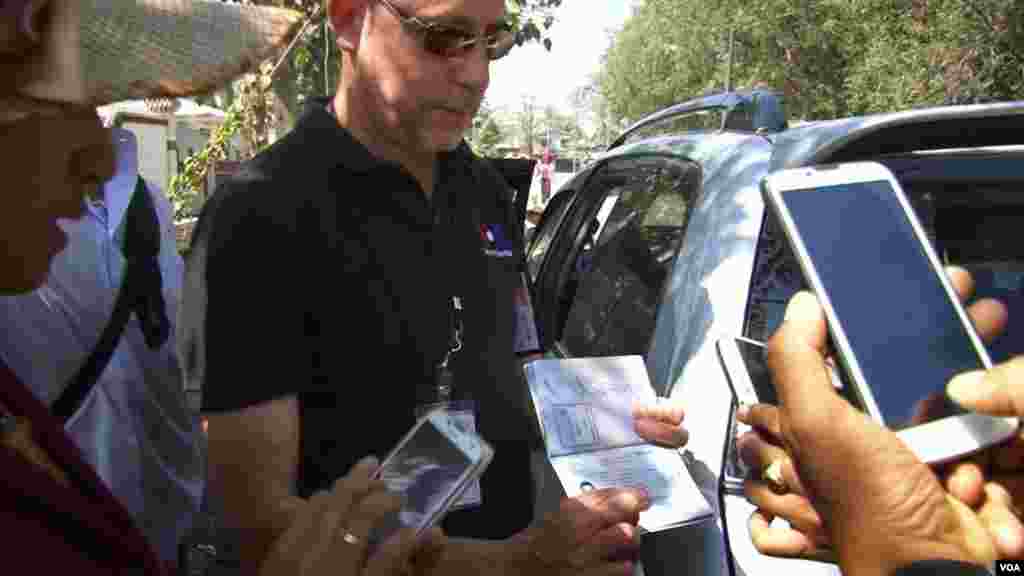 VOA Correspondent Steve Herman showing his Myanmar visa to officers believed to be from the immigration department, police, Special Branch and local authorities in Shwepyitha township. (Zinlaut Aung/VOA)