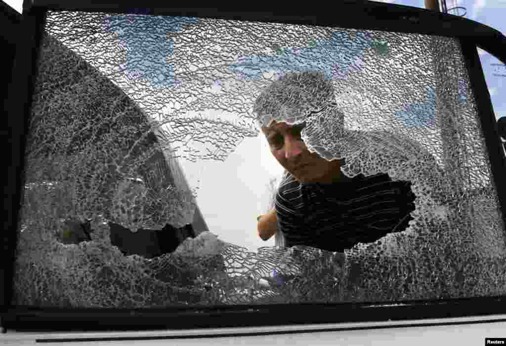 A local looks at a damaged vehicle following a gun battle in the rural settlement of Karlovka, west of Donetsk, Ukraine, May 23, 2014.