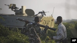 A Somali National Army soldier points at an African Union Mission in Somalia (AMISOM) armored personnel carrier during an advance into insurgent al-Shabab territory in Mogadishu, January 21, 2012.