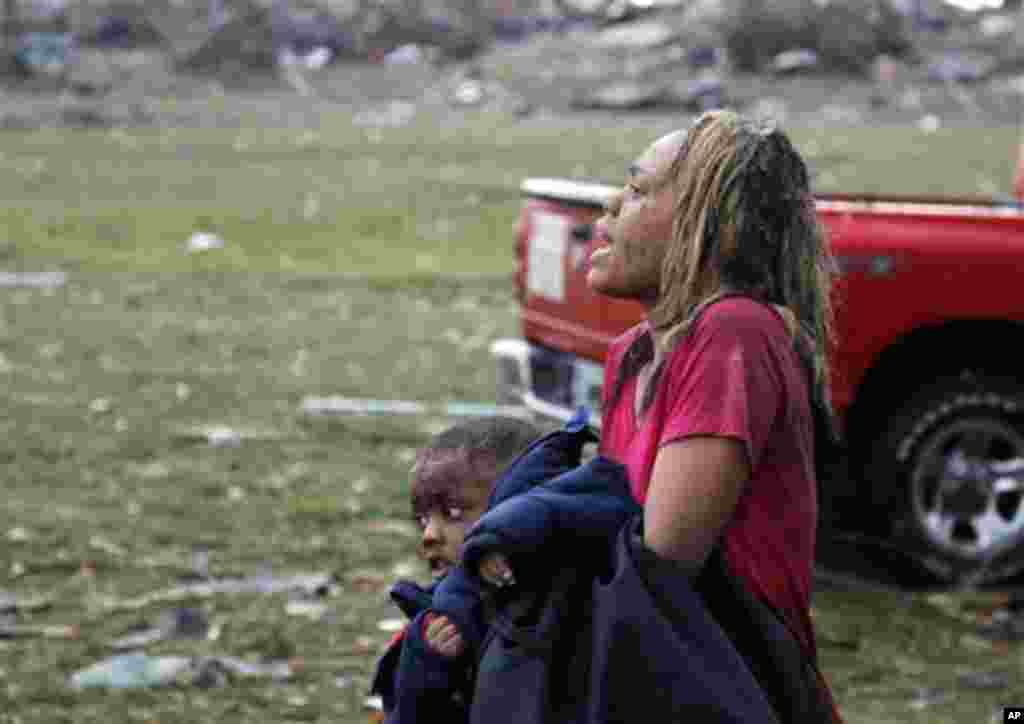 A woman carries an injured child to a triage center near the Plaza Towers Elementary School in Moore, Okla., Monday, May 20, 2013. 