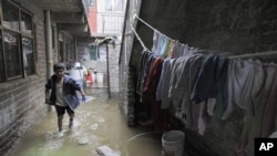 Ocatvio Diaz wades through sewage water flooding his home's patio after the Remedios sewage river overflowed on the outskirts of Mexico City, Mexico, July 1, 2011
