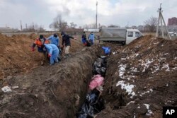 Dead bodies are put into a mass grave on the outskirts of Mariupol, Ukraine, March 9, 2022 as people cannot bury their dead because of the heavy shelling by Russian forces. (AP Photo/Evgeniy Maloletka)