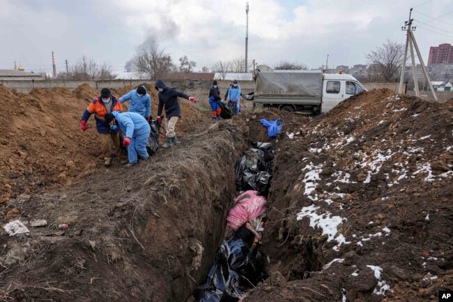 Dead bodies are put into a mass grave on the outskirts of Mariupol, Ukraine, March 9, 2022 as people cannot bury their dead because of the heavy shelling by Russian forces. (AP Photo/Evgeniy Maloletka)