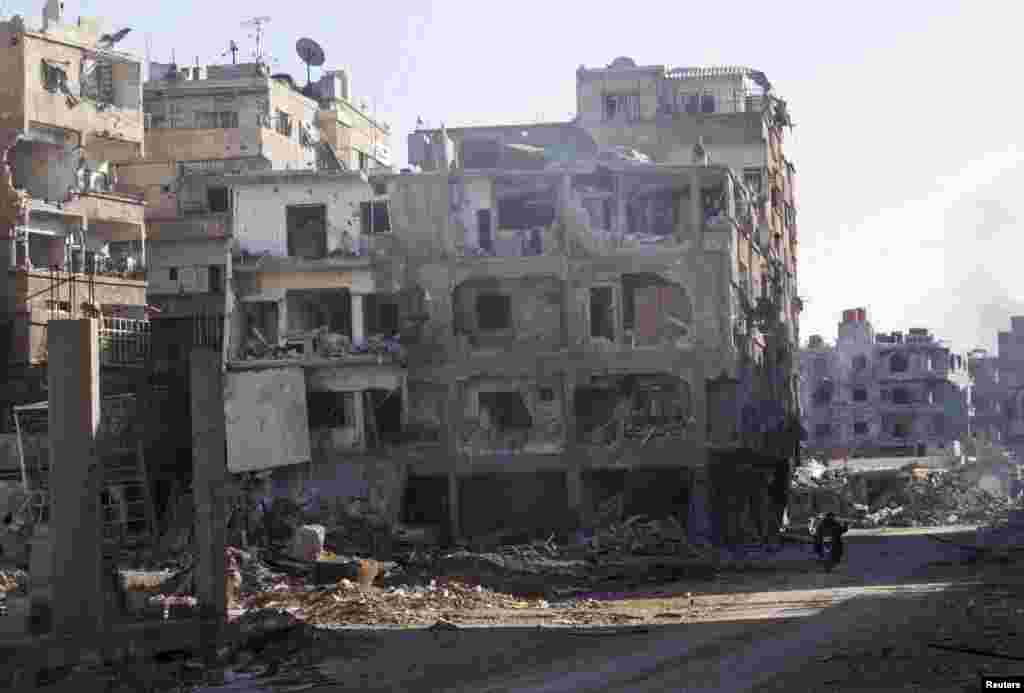 Men ride a motorbike past buildings damaged by what activists said was shelling by forces loyal to Syria's President Bashar al-Assad in Daraya, Jan. 15, 2014.