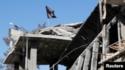 A flag of Islamic State militants is pictured above a destroyed house near the Clock Square in Raqqa, Syria, Oct.18, 2017.