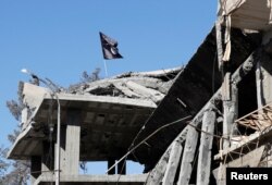 A flag of Islamic State militants is pictured above a destroyed house near the Clock Square in Raqqa, Syria, Oct.18, 2017.