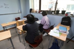 A North Korean refugee mother and a Chinese father, and her North Korean mother sit during an interview at the South-North Love School in Seoul, South Korea.