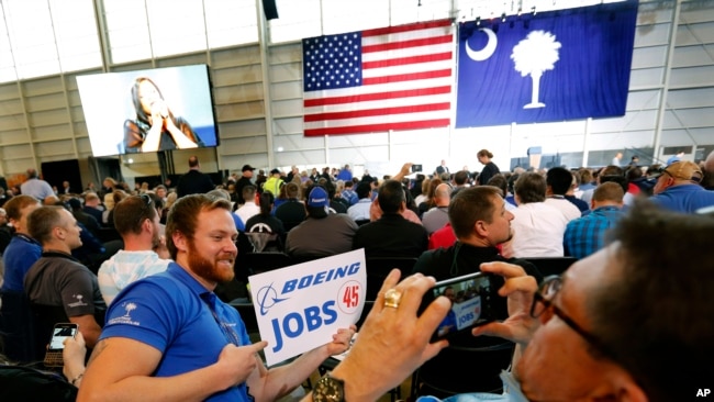 Trabajadores de Boeing se toman fotos mientras esperan con otros para que el presidente Donald Trump hable este 17 de febrero de 2017 en el edificio final de Boeing South Carolina en North Charleston.