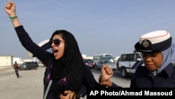FILE - Bahraini opposition activist Zainab al-Khawaja, left, gestures as she shouts "God is greater than any tyrant," while being arrested by police officers in Bahrain, Oct. 21, 2012.