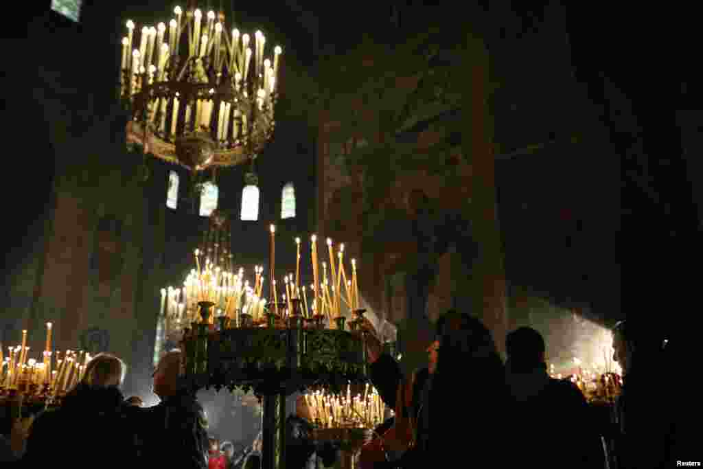 مردم در حال روشن کردن شمع ها در مراسم شب کرسمس در کلیسای شهر صوفیۀ بلغاریا.