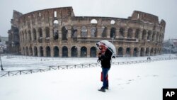 A man stands in front of the ancient Colosseum blanketed by the snow in Rome, Feb. 26, 2018. 