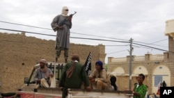 FILE - In this Aug. 31, 2012 file photo, fighters from Islamist group Ansar Dine stand guard in Timbuktu 