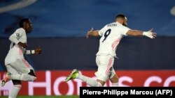 Real Madrid's French forward Karim Benzema (R) celebrates his goal during the UEFA Champions League round of 16 second leg football match in March. UEFA is worried about news of a new European soccer Super League. (Photo by PIERRE-PHILIPPE MARCOU / AFP)