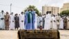 Des proches ainsi que des personnes en deuil tchadiennes et sénégalaises regardent un imam dire une prière sur le cercueil de feu l'ex-président tchadien Hissène Habré lors d'une cérémonie funéraire à Dakar, le 26 août 2021.