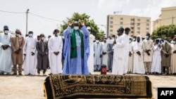 Des proches ainsi que des personnes en deuil tchadiennes et sénégalaises regardent un imam dire une prière sur le cercueil de feu l'ex-président tchadien Hissène Habré lors d'une cérémonie funéraire à Dakar, le 26 août 2021.