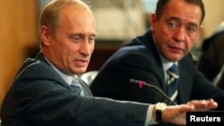 FILE - Russian President Vladimir Putin (L) and Mikhail Lesin, Russian press minister at the time, are seen at a meeting in Vladivostok, Russia, Aug. 24, 2002. Lesin, once considered a Putin associate, was found dead with blunt-force injuries in a Washington hotel room last November.