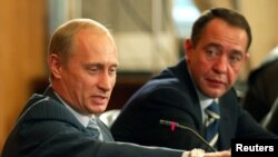 El presidente ruso Vladimir Putin y su vocero Mikhail Lesin, durante una reunión en Vladivostok, Russia, el 24 de agosto de 2002. 