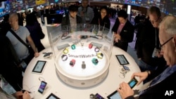 FILE - Trade show attendees examine the Sony Smart Watch 2 on display at the International Consumer Electronics Show, Jan. 8, 2014, in Las Vegas. High-tech tools can be used to help students cheat on exams, experts say.