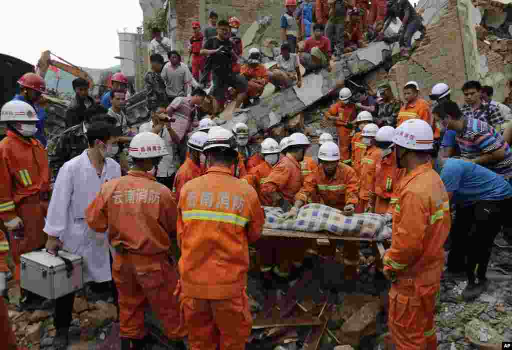 Rescuers prepare to carry away a young victim on a stretcher near a destroyed house following a massive earthquake in the town of Longtoushan in Ludian County in southwest China&#39;s Yunnan Province, Aug. 5, 2014.