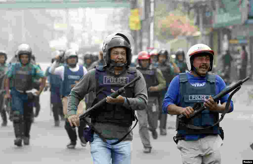 Police run during a clash with activists from Jamaat-E-Islami in Dhaka, Dec. 13, 2013.