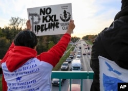 FILE - Opponents of the Keystone XL pipeline demonstrate on the Dodge Street pedestrian bridge during rush hour in Omaha, Neb., Nov. 1, 2017.