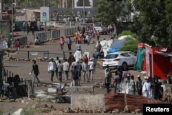Sudanese protesters walk between barricades on a road leading to the defense ministry compound in Khartoum, April 30, 2019.