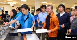 South Korean President Moon Jae-in waits in a line to get a meal after a hike with journalists, at the Presidential Blue House in Seoul, South Korea, May 13, 2017.