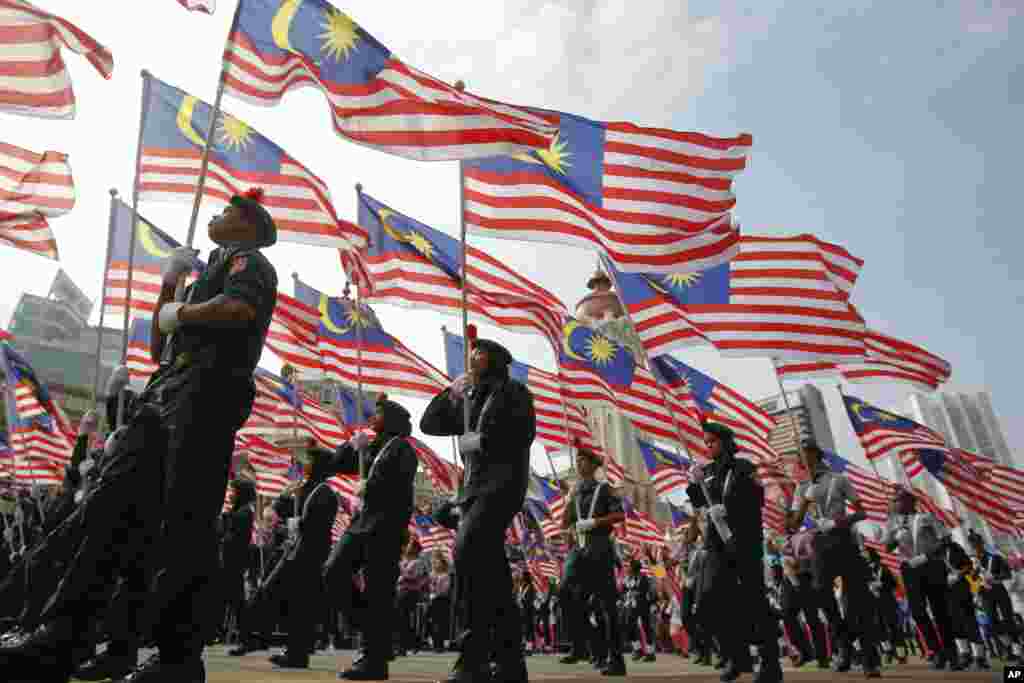 دانش آموزان با در دست داشتن پرچم مالزی، شصتمین سالگرد استقلال آن کشور را جشن می گیرند.