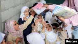Students receive books in their class at the teacher's house, who turned it into a makeshift free school that hosts 700 students, in Taiz, Yemen October 18, 2018. (REUTERS/Anees Mahyoub) 