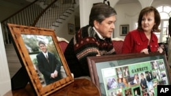 FILE-Sen. Gordon Smith, R-Ore., surrounded by photos of his son, Garrett, who committed suicide in 2003, pauses during remembrances of his son while his wife, Sharon, listens at their Pendleton, Ore., home on March 18, 2006. (AP Photo/Don Ryan)
